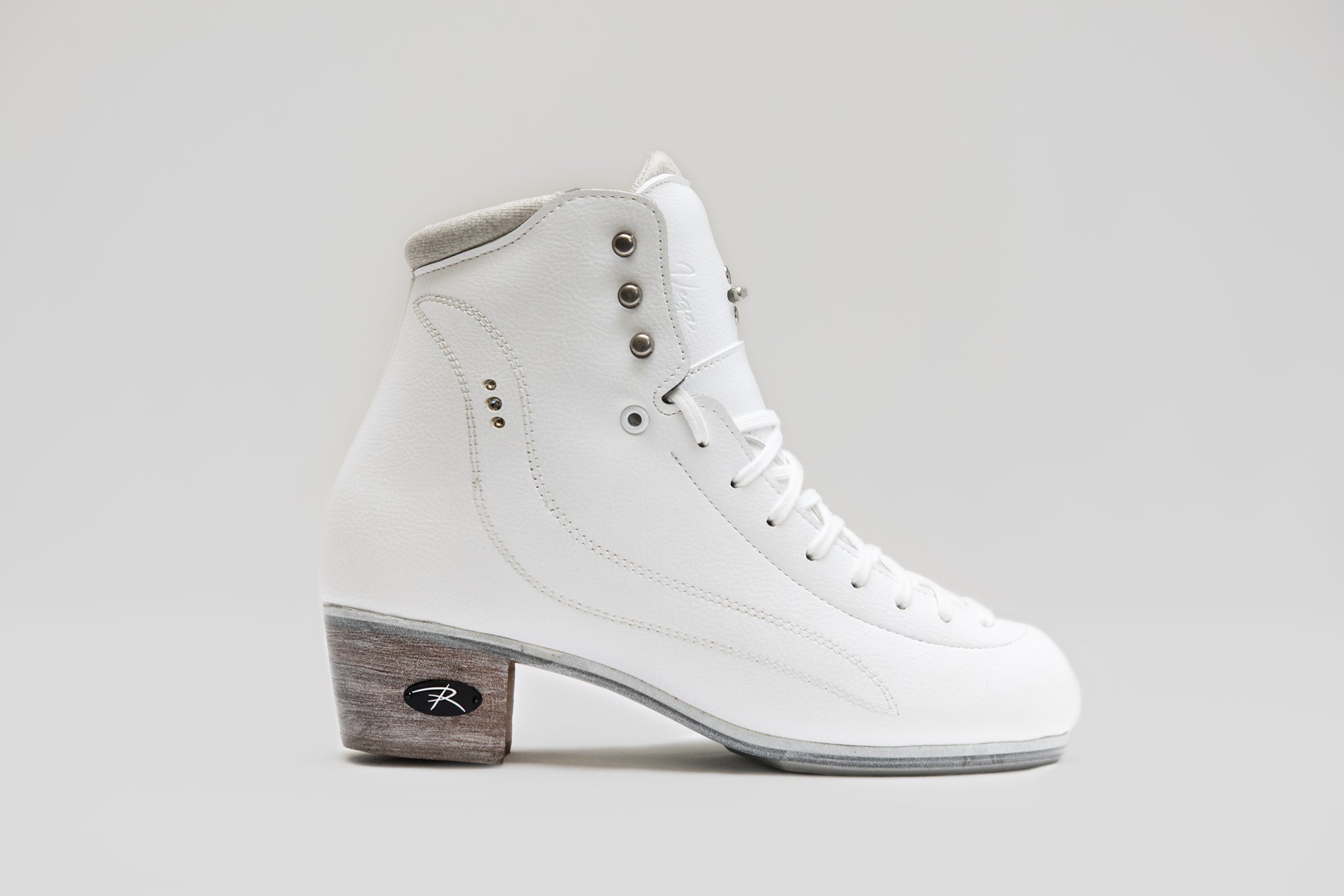 Side profile of Riedell Vega womens figure skate boot featuring white leather upper and reinforced ankle support for advanced skaters.