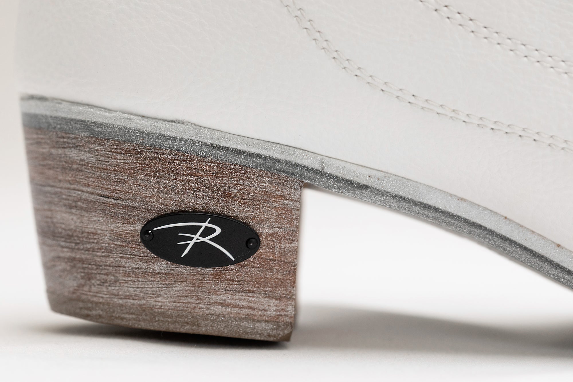 Close-up of Riedell Vega womens figure skate boot heel with wood-grain finish and Riedell logo plate for premium aesthetic.