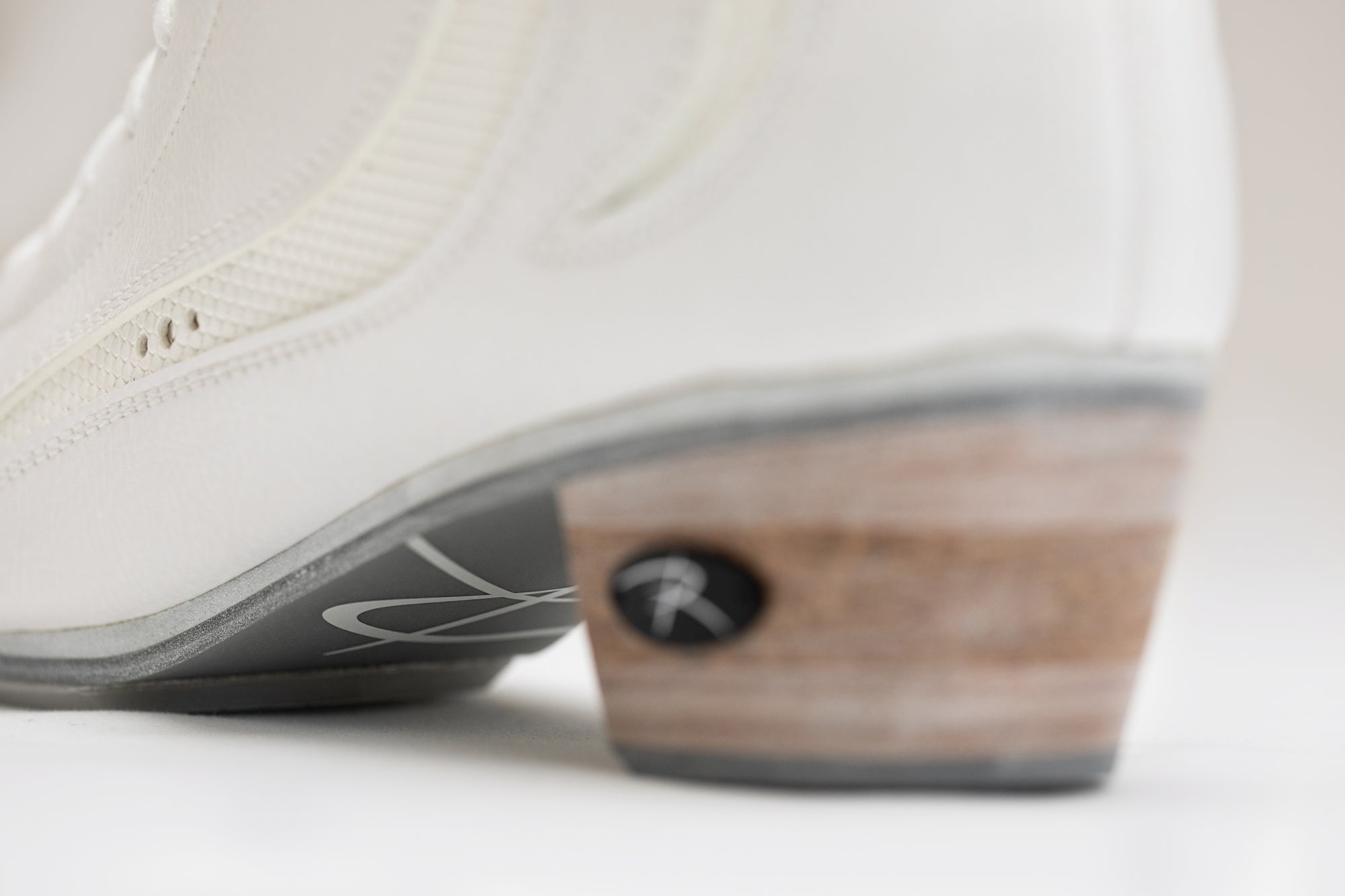 Angled heel view of Riedell Elara womens figure skate boots showing layered sole and stylish wood heel for stability and aesthetics.