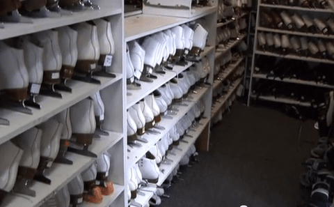 Rows of affordable and high-quality used ice skates in various sizes neatly arranged on shelves in a sporting goods store aisle.